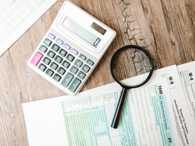 Formul&aacute;rios fiscais, calculadora e lupa sobre uma secret&aacute;ria